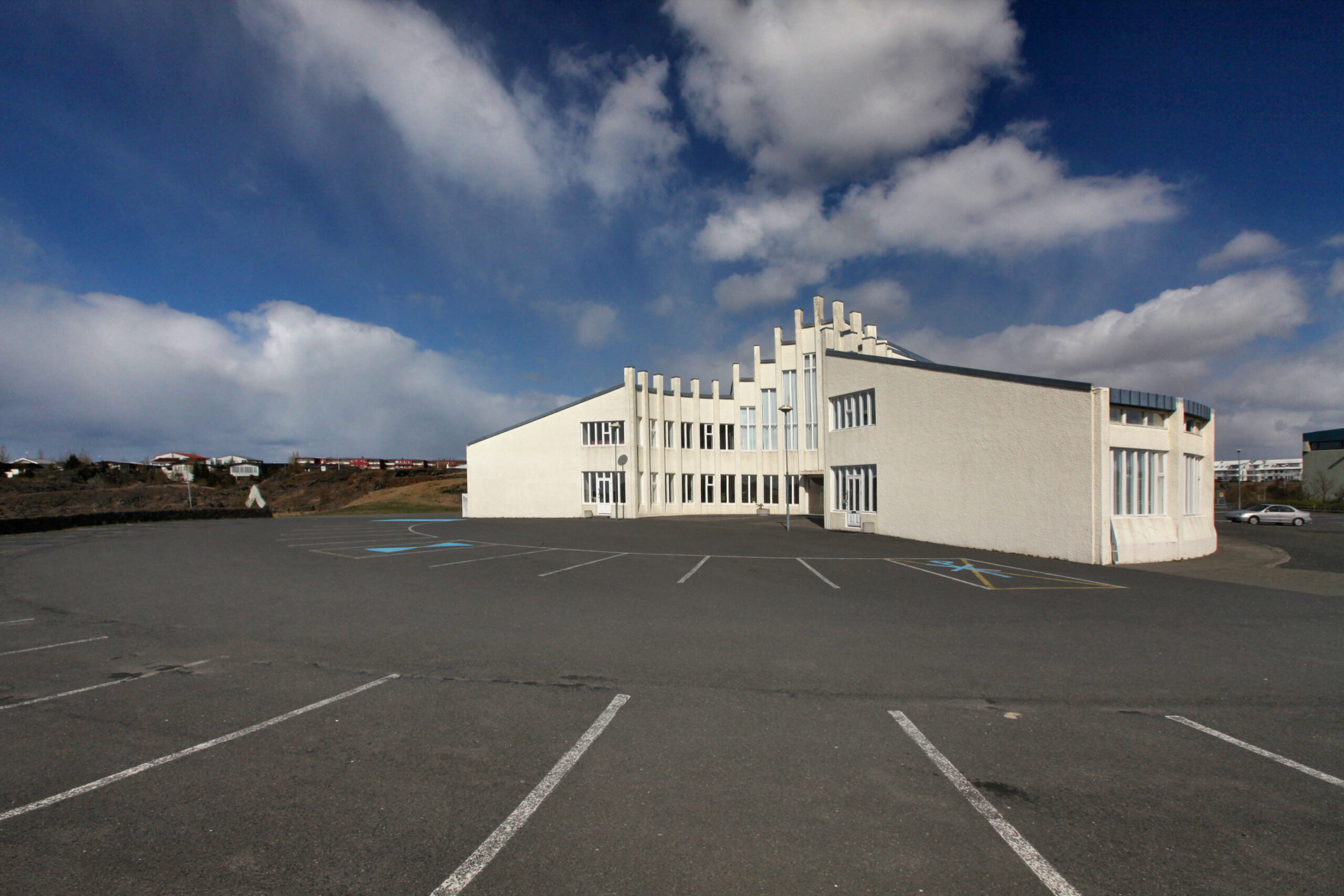 Víðistaðakirkja og bílastæði undir bláum himni.