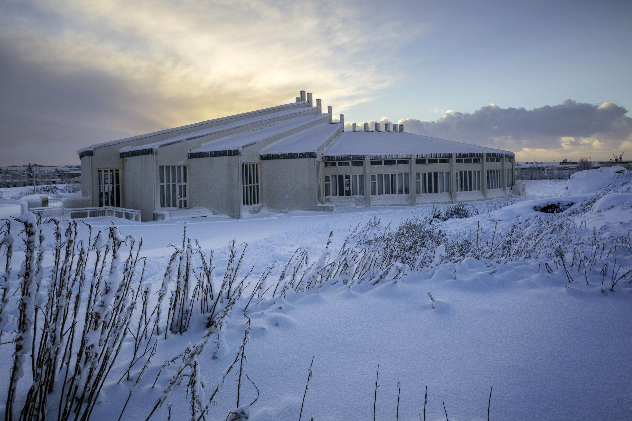 Víðistaðakirkja í snjó við sólsetur.